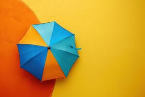 A vibrant umbrella rests against a sunny yellow and orange wall photo
