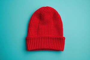 A vibrant red beanie lying on a turquoise background, showcasing its cozy texture and warmth photo