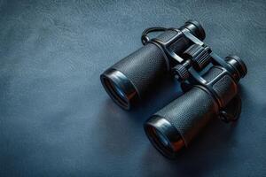 Discovering distant landscapes with sleek black binoculars on a textured surface photo