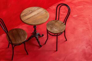 A cozy cafe corner with wooden furniture against a vibrant red backdrop photo