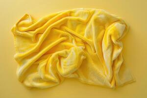 A vibrant yellow blanket drapes gracefully across a sunny background, casting soft shadows and inviting warmth and comfort photo