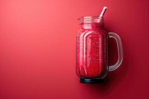 Vibrant raspberry smoothie in a glass jar against a bold red backdrop photo