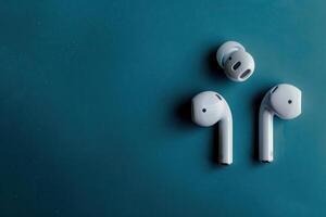 Modern wireless earbuds on a teal background, showcasing sleek design and innovative technology for an immersive audio experience photo