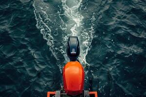 Vibrant orange motorboat gliding over deep blue water, leaving swirling wake in a serene lake during a tranquil afternoon photo