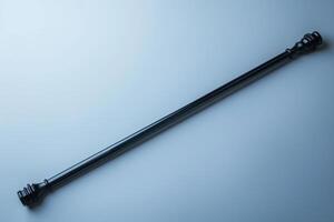 A sleek, elongated black wand resting on a smooth surface, capturing a minimalist aesthetic in soft lighting photo