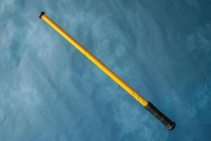 A vibrant yellow telescopic stick resting against a textured blue background photo