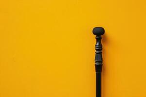 A black walking cane rests against a vibrant yellow wall during the golden hour, symbolizing support and resilience in everyday life photo