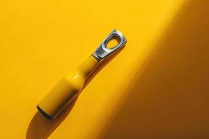 A vibrant yellow bottle opener resting against a sunny yellow backdrop, framed in a playful and artistic manner photo