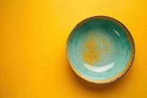 A vibrant turquoise ceramic bowl resting on a cheerful yellow backdrop, showcasing artistic craftsmanship and inviting culinary creativity photo