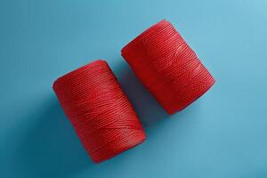 Vibrant red spools of thread resting on a soft blue surface, ready for creative crafting photo