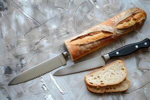 Fresh artisan bread resting on a textured surface, accompanied by a serrated knife and slices of crusty loaf in warm, inviting light photo