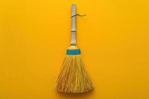 A bright yellow broom with a blue band stands against a vivid yellow backdrop, embodying the essence of cleanliness and simplicity photo