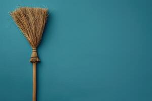 A rustic broom resting against a teal wall, evoking a sense of simplicity and charm in a cozy space photo