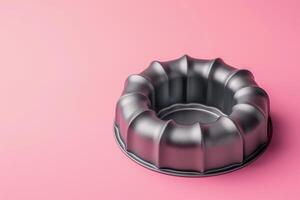 A sleek bundt pan rests on a vibrant pink backdrop, ready for baking delicious desserts photo