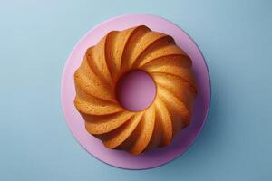 Swirl-patterned bundt cake on a pastel pink plate against a soft blue background photo