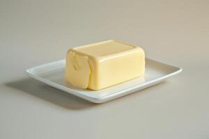 A creamy block of butter resting on a simple white plate in soft, natural light photo