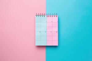 A spiral-bound calendar rests on a pastel pink and blue background, suggesting a fresh start or new beginnings in planning photo