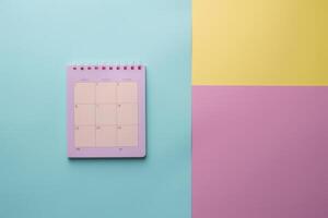 Colorful desk setup featuring a monthly calendar on a pastel background during a bright afternoon photo