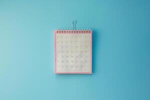 A colorful desk calendar hanging against a bright blue wall, marking important dates and events for the month ahead photo