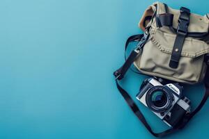 A vintage camera resting on a teal surface with a stylish canvas bag, ready for an adventure into the world of photography photo