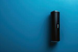 A sleek black cylindrical object on a vibrant blue surface, casting subtle shadows in soft lighting photo