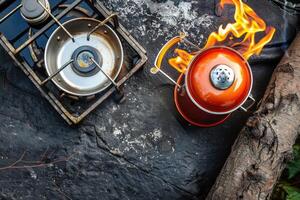 A vibrant kettle boils over a rustic camp stove surrounded by natural textures in the warm glow of midday sunlight photo