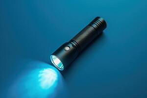 A sleek black flashlight illuminating a vibrant blue surface in a dimly lit environment photo