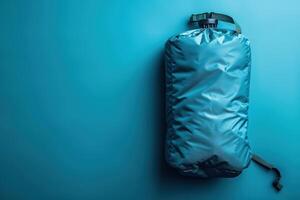 Compact teal travel bag resting on a vibrant blue background, perfect for adventures and outdoor excursions photo