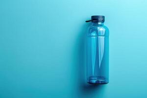 A lone blue water bottle rests against a vibrant aqua background, capturing a moment of simplicity and hydration photo