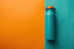 A vibrant teal water bottle rests against a split orange and teal backdrop, creating a striking visual contrast in a minimalist setting photo