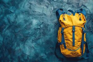 Bright yellow backpack resting on an artistic teal background, capturing adventure and style in a modern urban setting photo