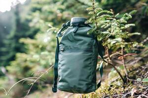 Exploring nature with a durable green backpack resting against a pine tree in a lush forest during daytime photo