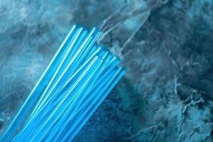 Vibrant blue glass tubes glisten under soft lighting against a textured surface photo