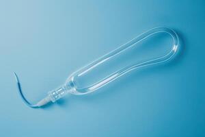 A transparent water hose with a curved tip rests on a soft blue background, reflecting light and showcasing its smooth design photo