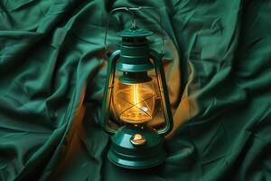 A vintage lantern glows warmly amidst emerald-green fabric, evoking a sense of nostalgia and tranquility photo