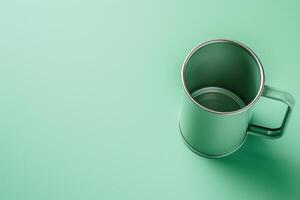 A sleek metallic mug rests on a smooth mint green surface, inviting a cozy sip of warmth photo