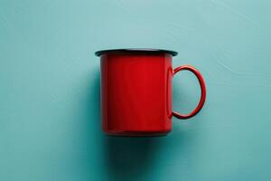 A vibrant red enamel mug rests on a soft teal surface, inviting cozy moments with warm beverages photo