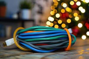 Colorful extension cord coiled neatly in front of a decorated Christmas tree with soft glowing lights photo