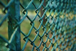 Close-up view of a green chain-link fence in a park during daylight photo