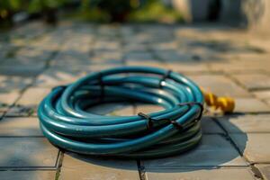 A coiled garden hose resting on a patio in the morning sunlight photo