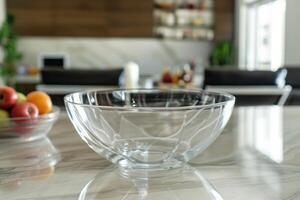 Clear glass bowl positioned on a polished marble countertop in a modern kitchen with fruit and a stylish decor background photo