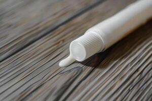 Squeeze bottle of cream on wooden surface dripping slowly photo