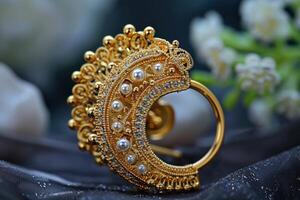 Ornate gold earring with pearls displayed on a dark fabric background photo