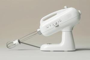 White electric hand mixer on a neutral background with whisks attached in a kitchen setting photo