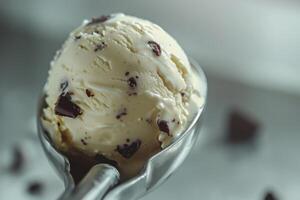 Creamy vanilla ice cream scoop with chocolate chunks on a silver scoop photo