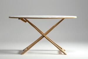 Folding wooden table with a round top displayed against a plain background, highlighting its minimalist design and functionality photo