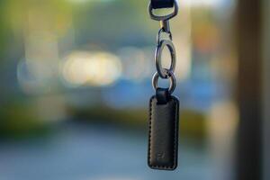 Close-up of a black leather keychain attached to a keyring hanging outdoors on a sunny day photo