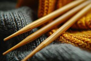 Knitting needles resting on a textured grey and yellow knitted fabric photo