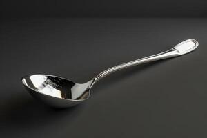 Shiny stainless steel ladle resting on a dark countertop photo
