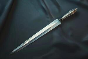 Antique dagger with intricate handle resting on dark fabric photo